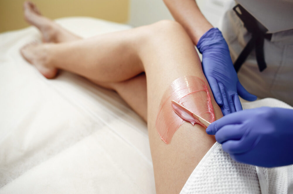 Profissional Rosa Sperandio pasando cera na perna de uma cliente para depilação em duque de caxias