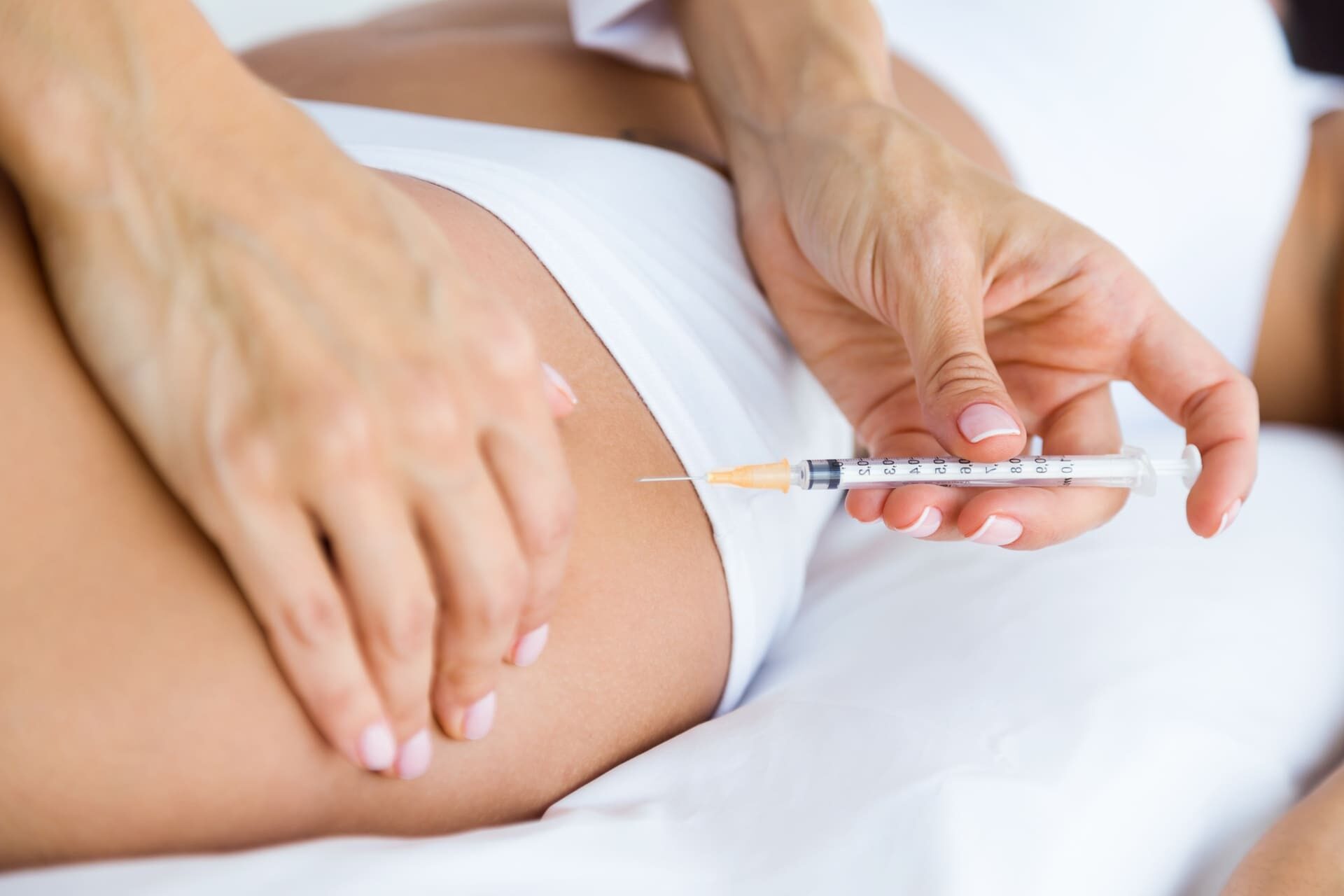 Profissional da Rosa Sperando Estética, com agulha proxima a coxa da Cliente para procedimento de Harmonização corporal em Duque de Caxias